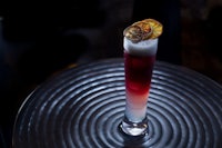 a cocktail with a red drink on top of a table