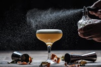 a person is pouring a drink into a glass