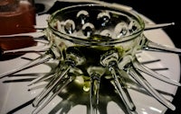 a glass bowl with a spike in it on a plate