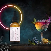a bottle of lavender oil next to a cocktail and blueberries