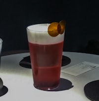 a glass of red drink on a table next to a glass of water