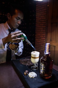a bartender pouring a drink into a glass