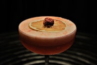 a cocktail with a lemon garnish on top