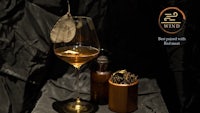 a glass of whiskey with a leaf on it